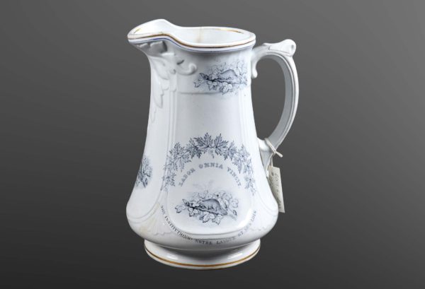 Large white earthenware pitcher decorated with blue drawings of maple leaves and a beaver.
