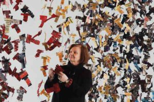 The artist Carole Simard Laflamme alongside her multicolored suspended textile sculpture «La robe des nations».